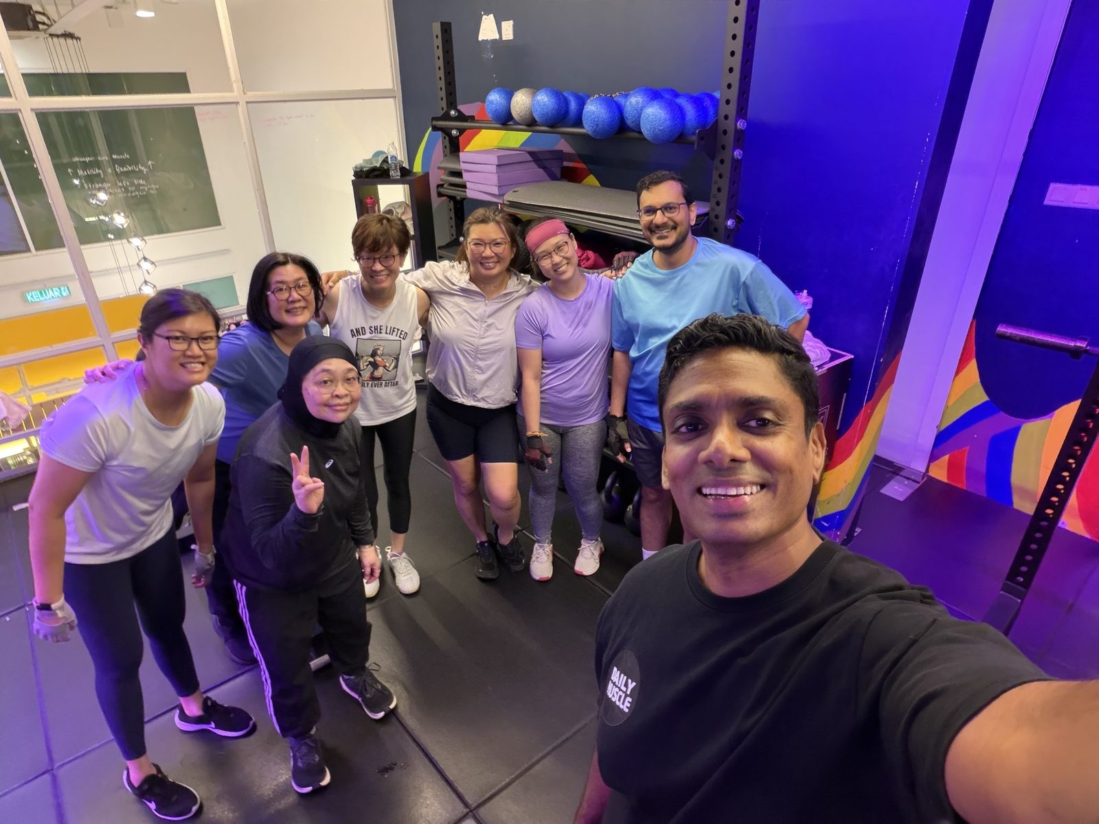 Noel and a group of Heroes smiling together inside DailyMuscle LightHouse after a session